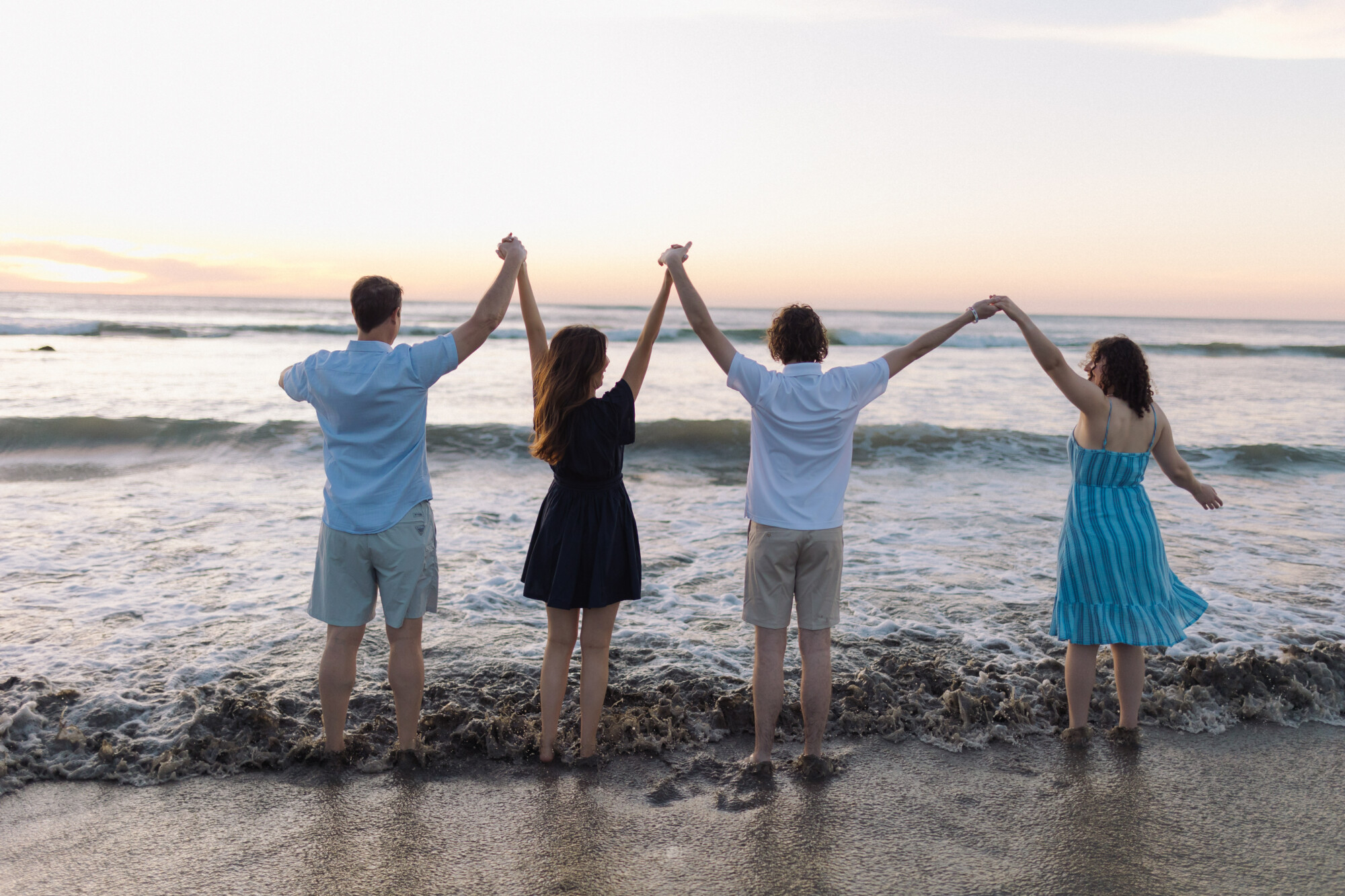 family holding hands in celebration on the beach on vacation after ROOF