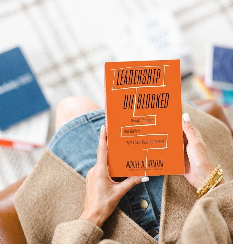 Leadership Unblocked book cover by Muriel Wilkins held by a leader in a home office